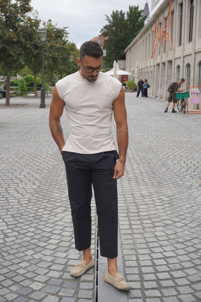 Model v bež majici brez rokavov in črnih hlačah