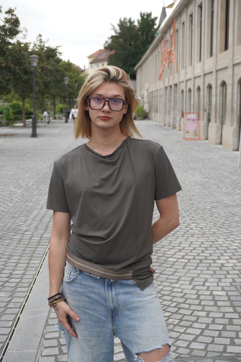 Model v oljčno zeleni asimetrični majici in jeansu